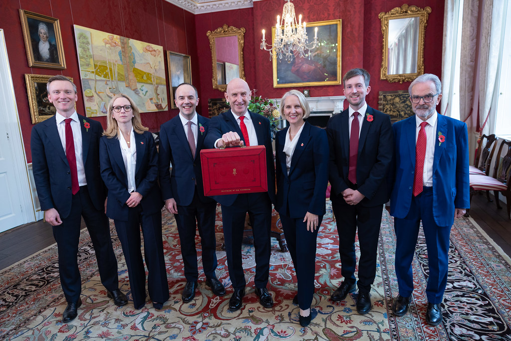 Chancellor John Healey holding the red Budget box alongside his Treasury ministerial team at 11 Downing Street